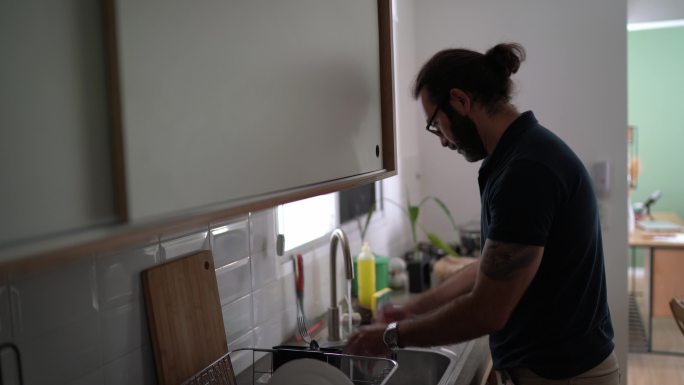 一位成年男子在家洗碗的肖像
