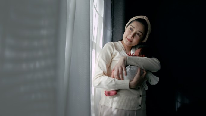 当单身母亲站在家里的婴儿房里抱着婴儿时，男婴睡着了。绞痛、精神病、， 情绪和身体发展