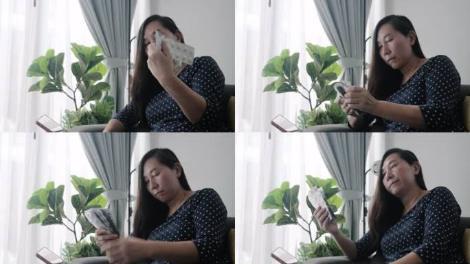 亚洲成年女性坐在家里靠窗的沙发上，检查血压后，准备服用抗高血压药，这是一种生活方式理念。