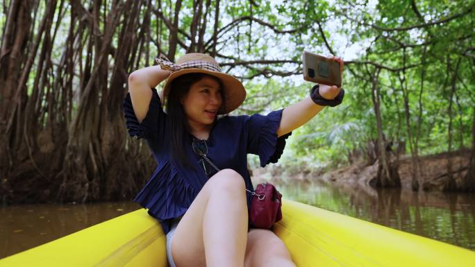 自然旅游活动旅行皮划艇，女性划桨透明皮划艇在泥炭沼泽森林湿地，亚洲女性在夏季探索红树林时休闲微笑