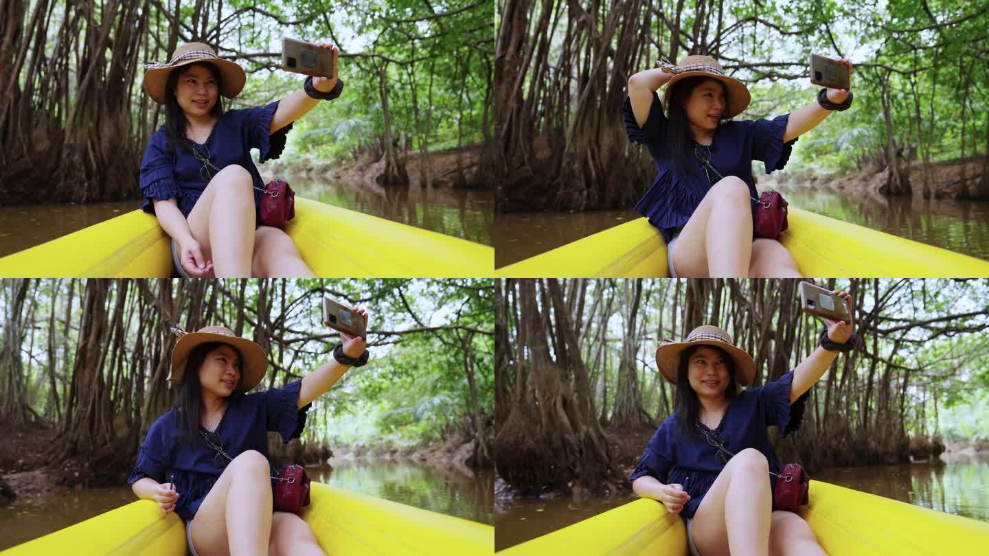 自然旅游活动旅行皮划艇，女性划桨透明皮划艇在泥炭沼泽森林湿地，亚洲女性在夏季探索红树林时休闲微笑