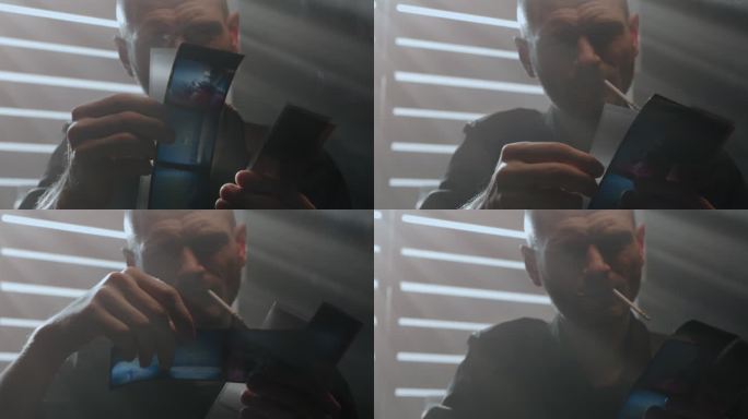 一名侦探把电影照片放在手里，抽起烟来