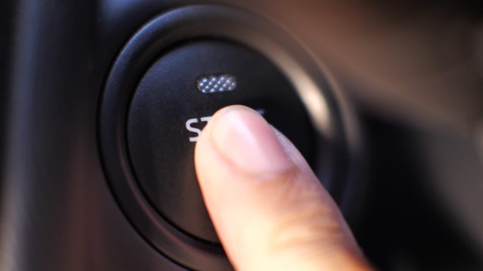 手指推动发动机启动按钮，推动汽车启动