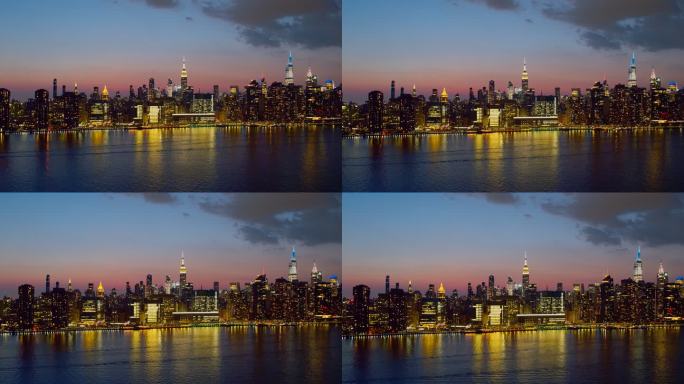 日落时分，纽约市曼哈顿中城东河对岸的远处全景夜景。具有平移转发运动的空中视频。