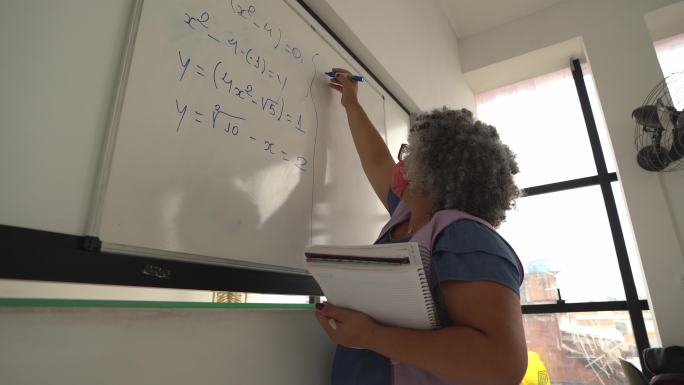老师戴着口罩在黑板上写字