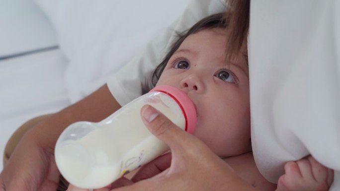 婴儿奶瓶喂养和躺在母亲大腿上