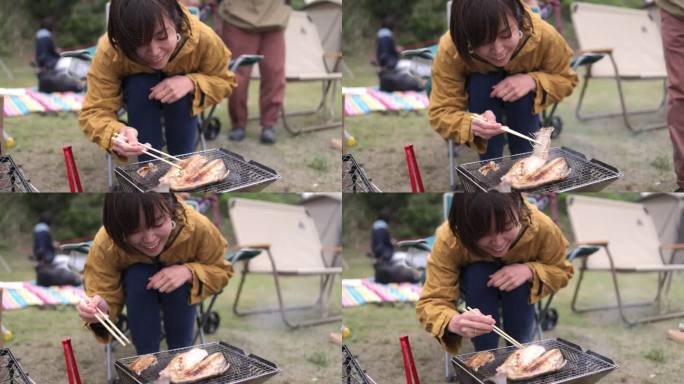 一名年轻女子在营地从烤鱼中取出鱼刺