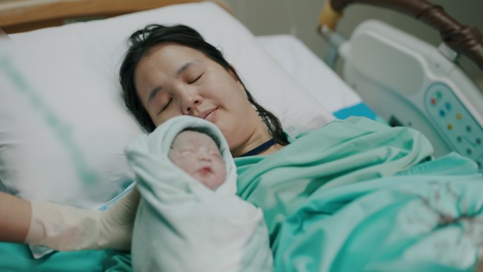 亚裔母亲和她的婴儿在医院的产房出生。