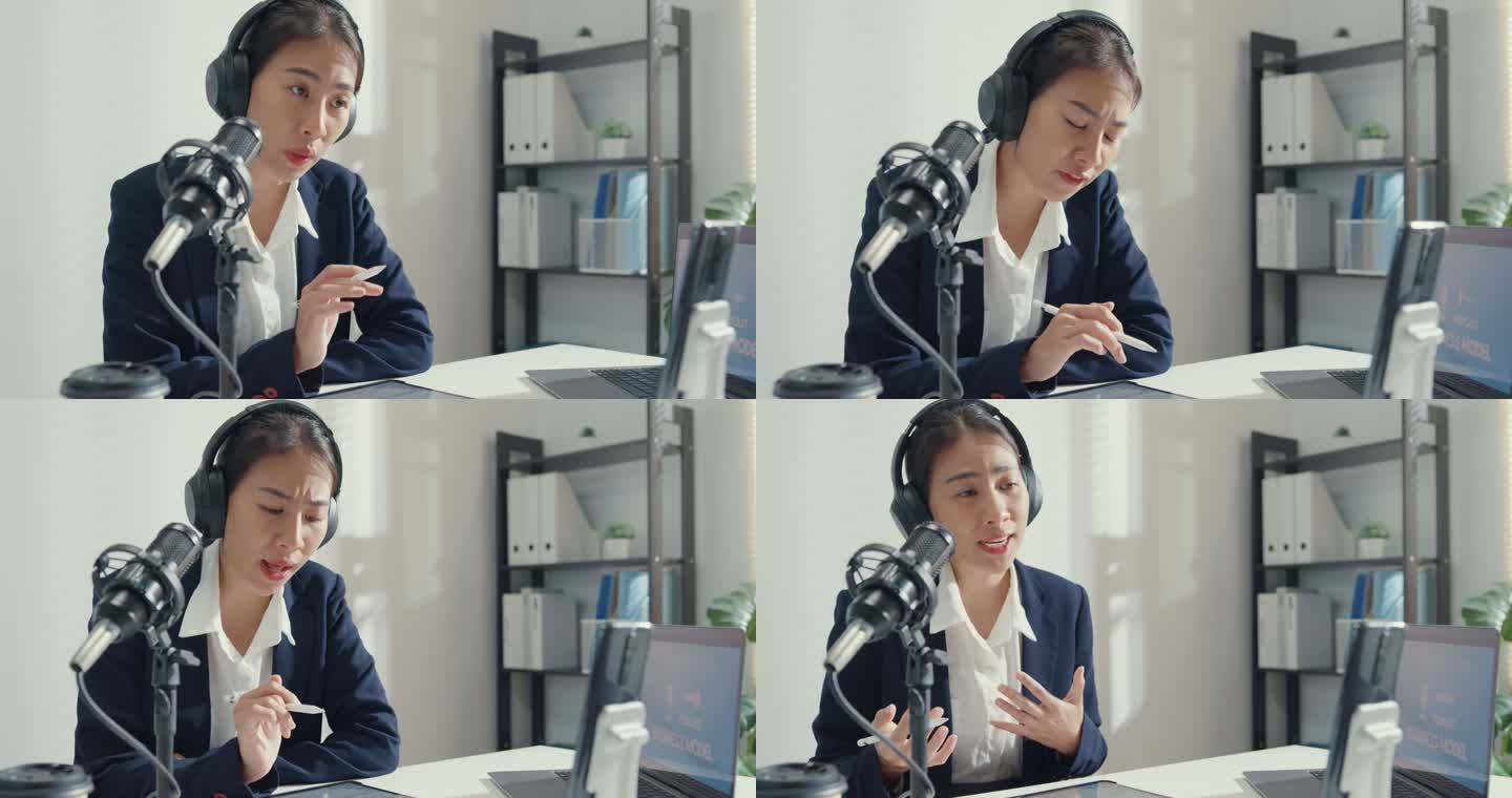 年轻的亚洲女商人用智能手机录制内容，并在工作室办公室用笔记本电脑播放播客。