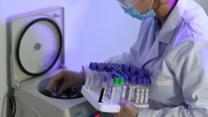 亚裔中国女性实验室助理医生在离心机上取出小瓶血液样本