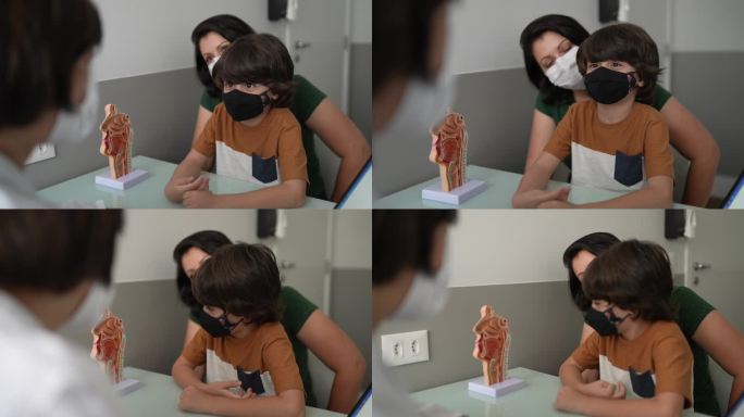 医生和他的母亲在一家诊所照顾男孩-使用口罩