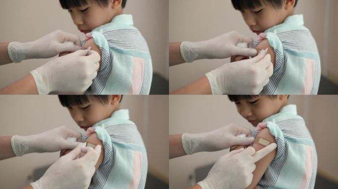 男医生在接种疫苗后给男孩的手臂缠上绷带。
