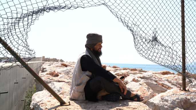 一名难民男子坐在栅栏后面的4K视频片段