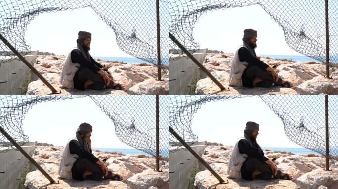一名难民男子坐在栅栏后面的4K视频片段