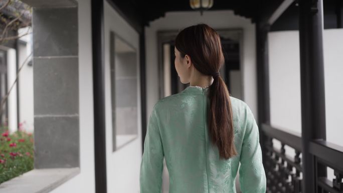 年轻旗袍女子步行穿过中式合院门廊