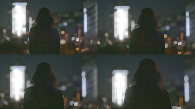 一名女子晚上在城市屋顶上的4k视频片段