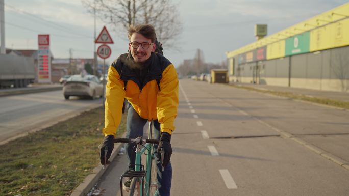 穿着黄色夹克衫的白人年轻人，骑着自行车在自行车道上通勤
