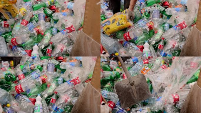 废物回收。工人用铲子推彩色塑料瓶