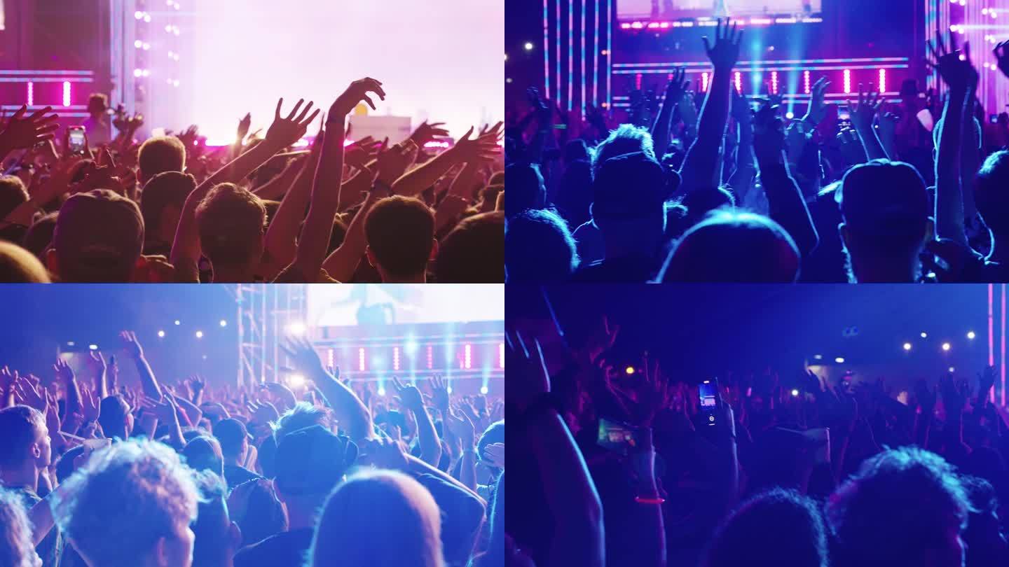 群众在音乐节上欢呼。双手举在空中。彩色照明和烟雾