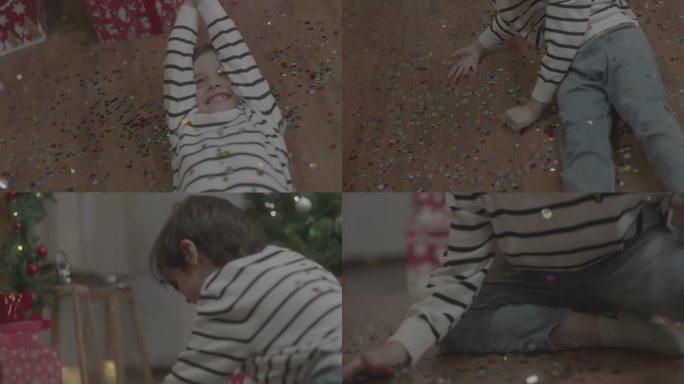 头戴圣诞帽的小男孩快乐的躺地上玩彩纸礼花