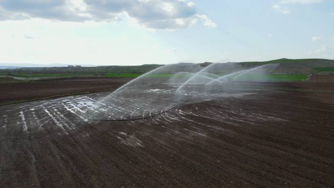 鸟瞰灌溉系统浇灌农田，鸟瞰灌水系统在日落时浇灌麦田