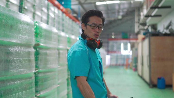 亚洲中国仓库工厂蓝领工人抬着空油箱，看着镜头，脸上肌肉舒展