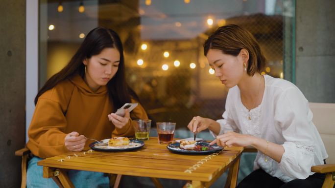 女性朋友在咖啡馆见面，但只使用她们的智能手机。