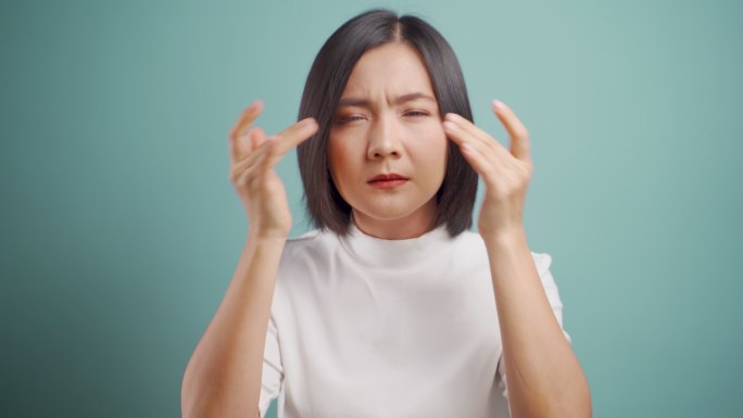 一位亚洲女性眼睛疼痛，站在蓝色背景下与世隔绝。医疗保健概念。4k视频。