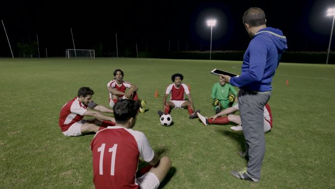 拉丁美洲教练使用平板电脑与一队足球运动员谈论下一场比赛的策略