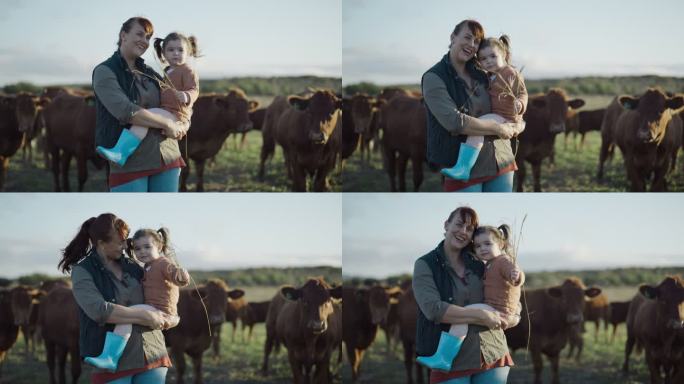 母女俩在农场里的画像，靠近他们的奶牛。农村单身母亲微笑着和她的小孩站在一起，手里拿着干草，对着相机挥