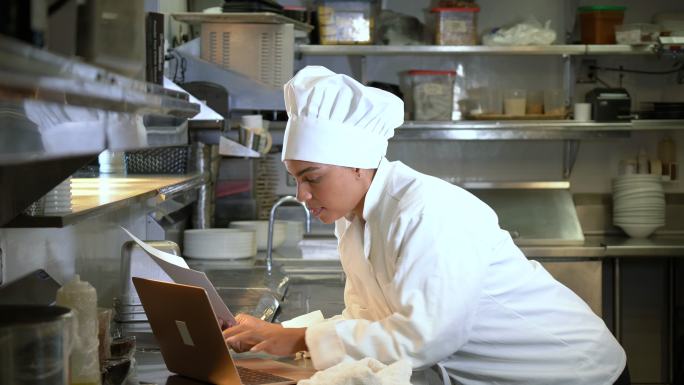 商业厨房女厨师使用笔记本电脑