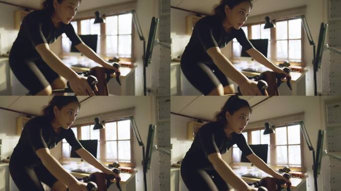 亚洲女自行车手，她正在家里锻炼。她骑自行车模拟器。