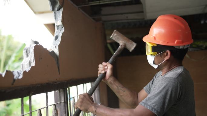 施工人员戴防护面罩用大锤拆墙