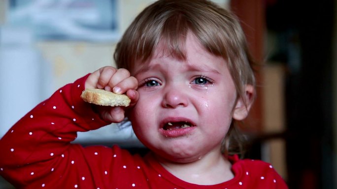 一个哭泣的小女孩拿着干面包的肖像