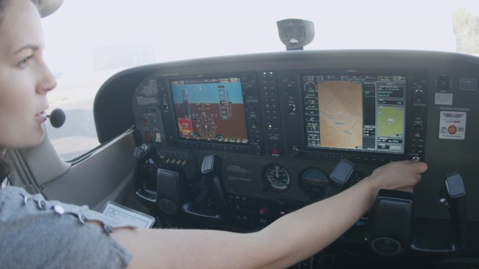 年轻成年女飞行员在多功能飞行控制显示器上加载飞行计划