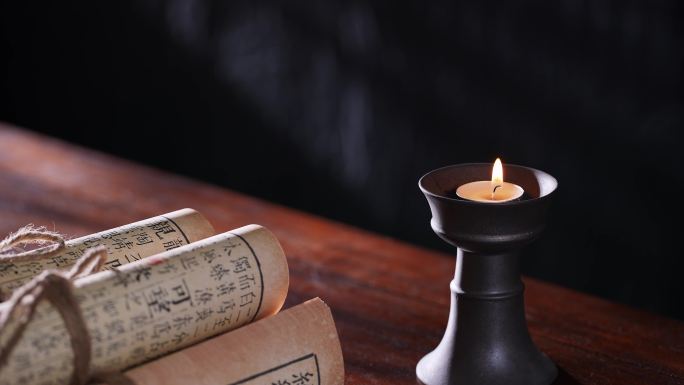 古代书房书桌上燃烧的蜡烛和古书
