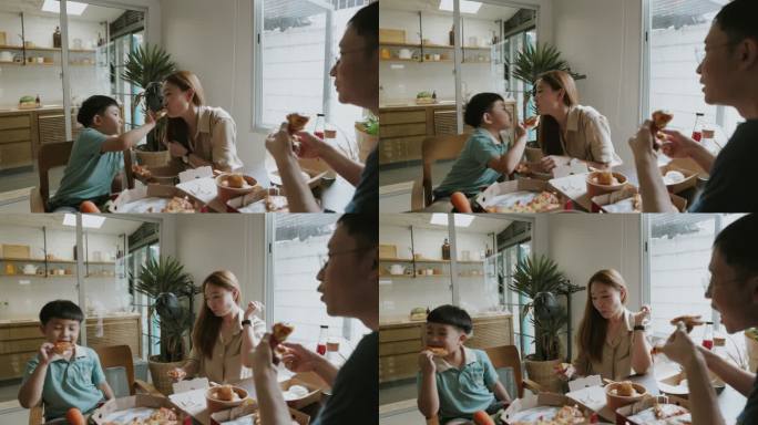 一个可爱的泰国男孩在周末和妈妈在家共进午餐时，与妈妈分享他的披萨。