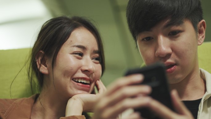 情侣们在飞机上等待时玩智能手机。