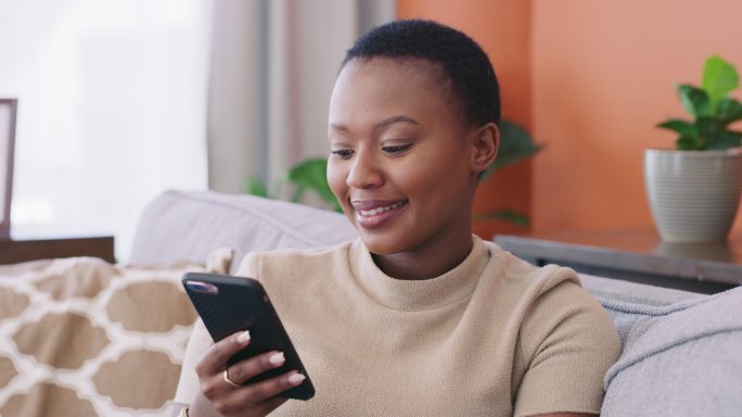 一个年轻女性在家沙发上使用信用卡和智能手机的4k视频