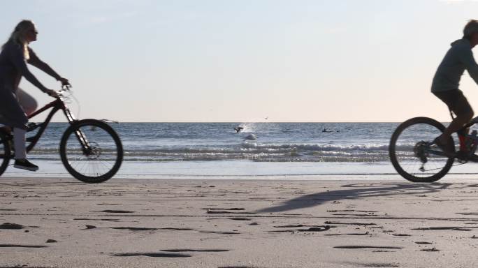 自行车夫妇在空荡荡的海滩上享受自由时刻