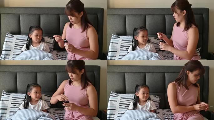 一位亚洲母亲将止咳糖浆药倒进清澈的勺子里给女儿吃