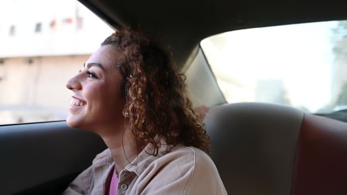 快乐的中东年轻女子望着后座窗户