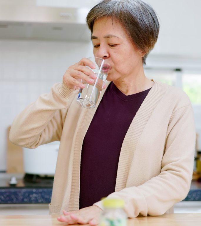 亚洲老年妇女服药吃药拿水送药居家老年人生