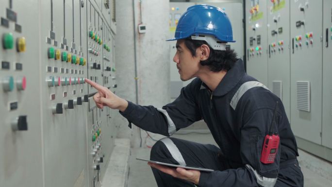 一名电工工程师在工业工厂的控制室、操作员站网络中工作、检查和记录电气保护继电器参数。