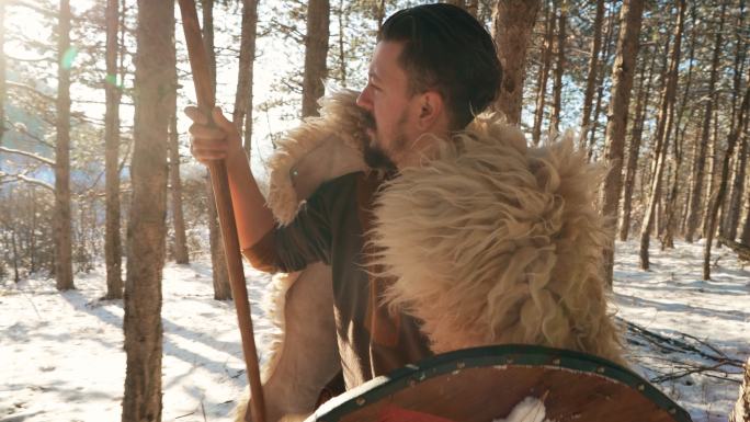小心的中世纪武士，冬天带着矛和盾牌在森林里行走