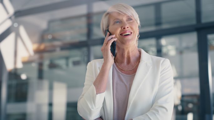 一位成熟的女商人站在办公室里打电话。自信的女性企业家和领导者在电话中与客户或同事进行商务交易或安排会