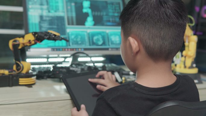 教育主题：数字平板电脑上的男孩控制机器人手臂、科学工程、教育、技术