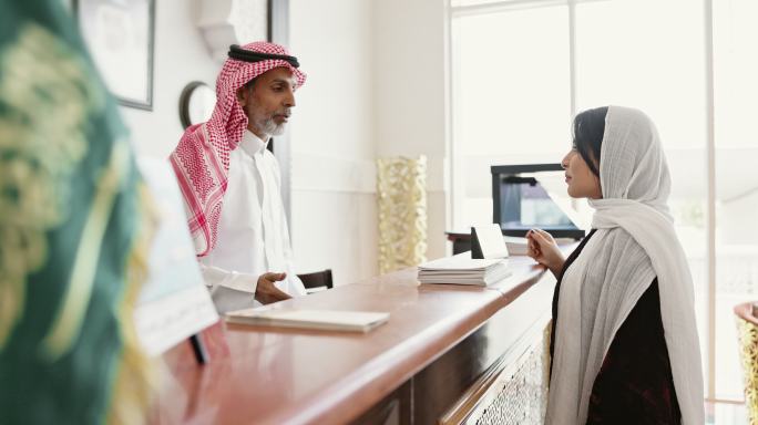 女性旅行者与沙特酒店接待员交谈