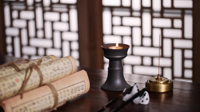 古代书房书桌上燃烧的蜡烛和古书