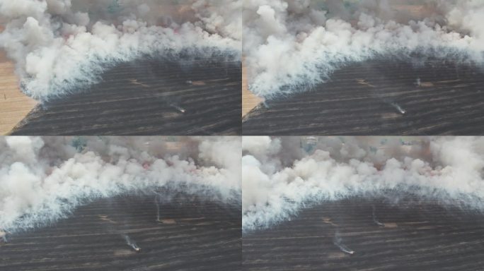 农田起火。鸟瞰图，中央上方。从直升机上观看。棕灰色烟雾。红色火焰和消防队员。水平和旋转摄像机运动。